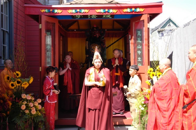 Photo of Akoulama Rinpoche and others standing in front of the just installed statue of Ven. Guan Yu at His shrine in the courtyard of Hua Zang Si.