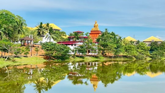 Photo of the Bhutanese Center at NIIBS in Sri Lanka next to the Lake with the 1,000 Buddha Statue Building in the background.
